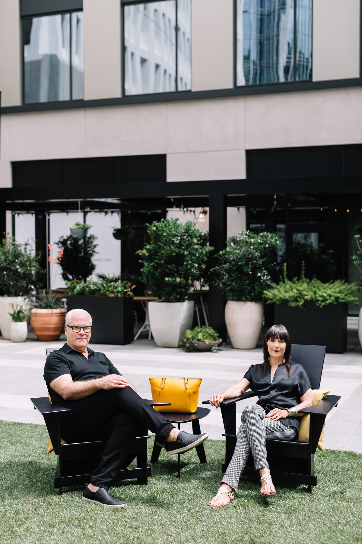 Kevin Steward and Niki Paris seated together on a lawn outside a modern Atlanta home